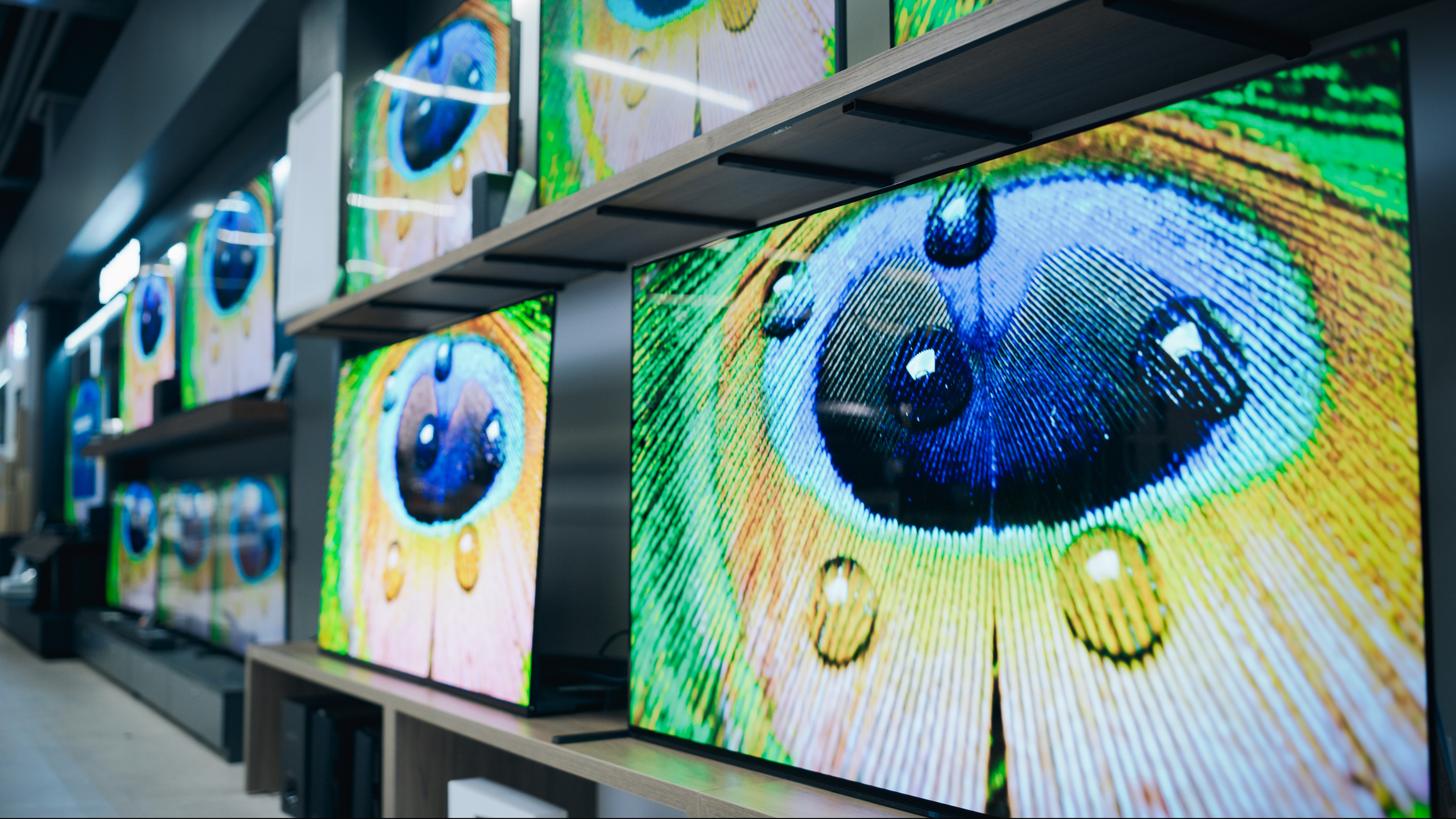 Wide Angle View of Retail Home Electronics Store Displaying Array of Different Modern TVs. Colorful Flat-Screen Televisions Showcase Cutting-Edge Color Quality in Modern Showroom Setting